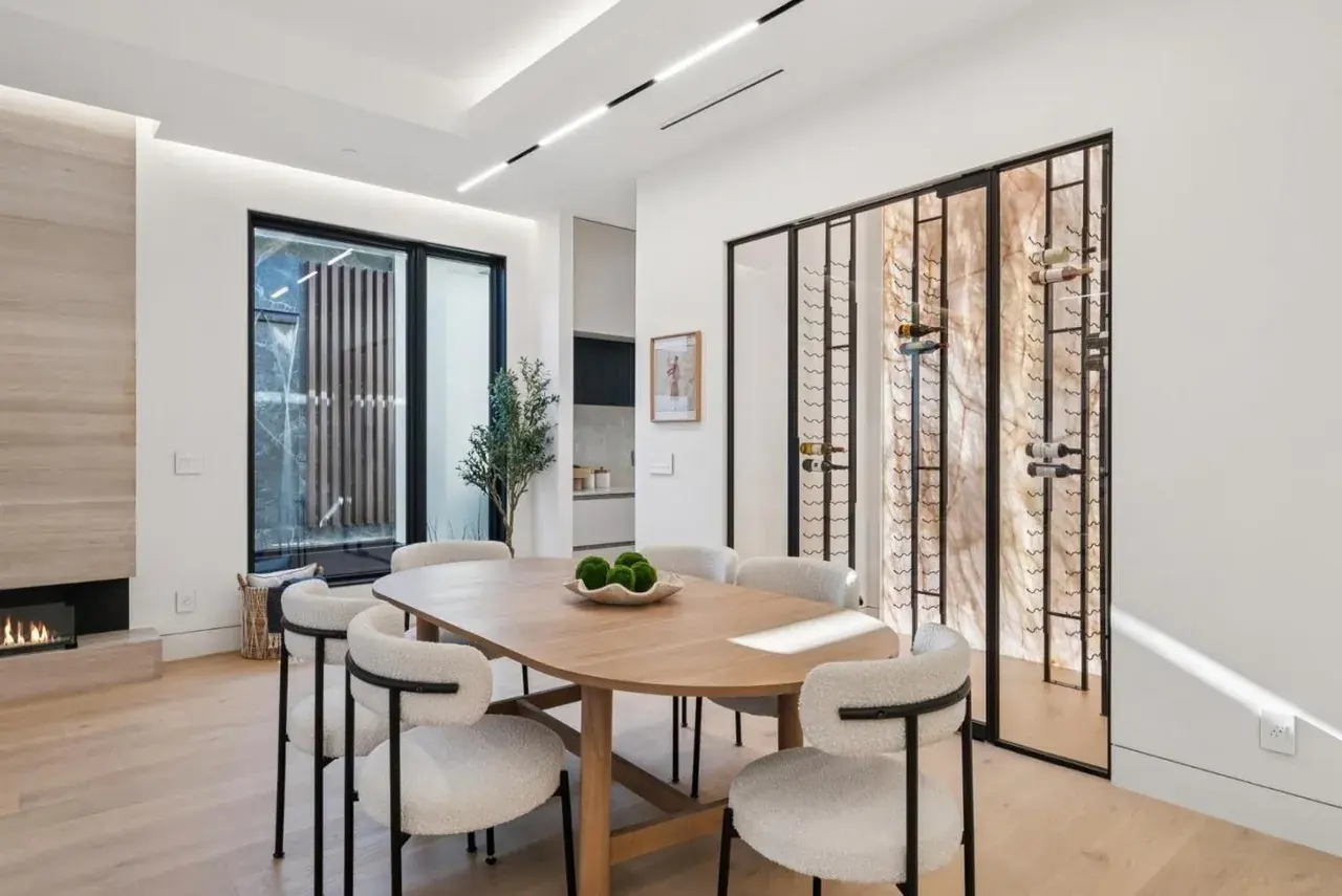 Dining area with a cove lit ceiling and a backlit stone wine wall alongside