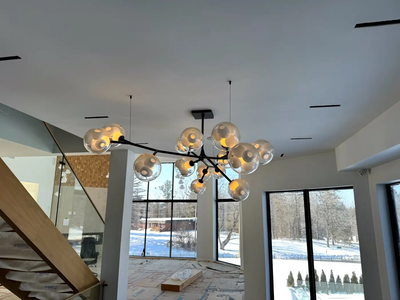 Dining area and stair under a branch chandelier with globe shades