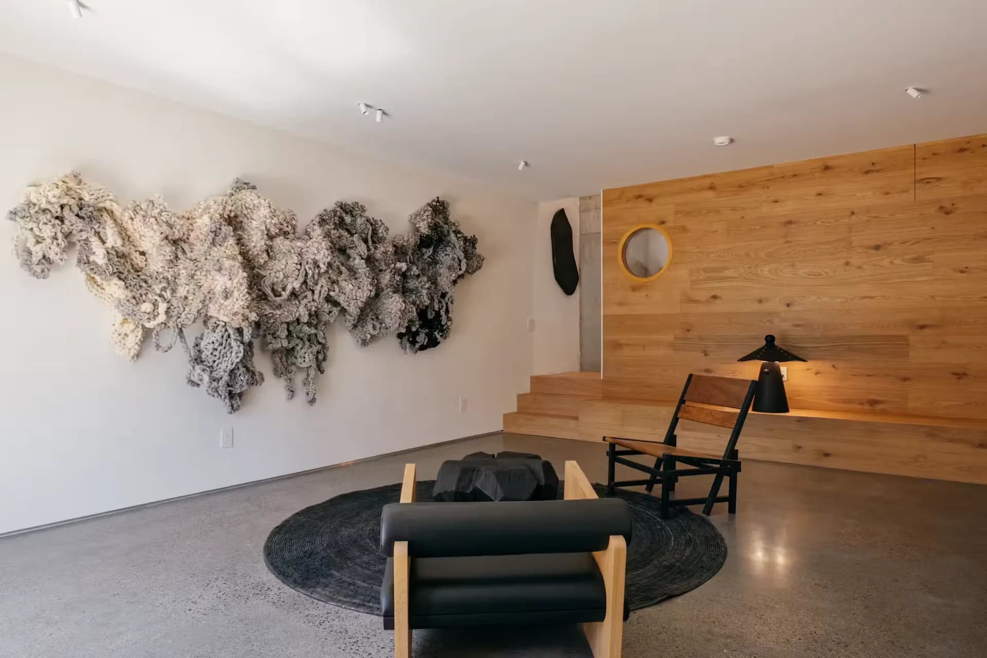 Living room with a timber-clad wall, a round mirror and steps up to the next level