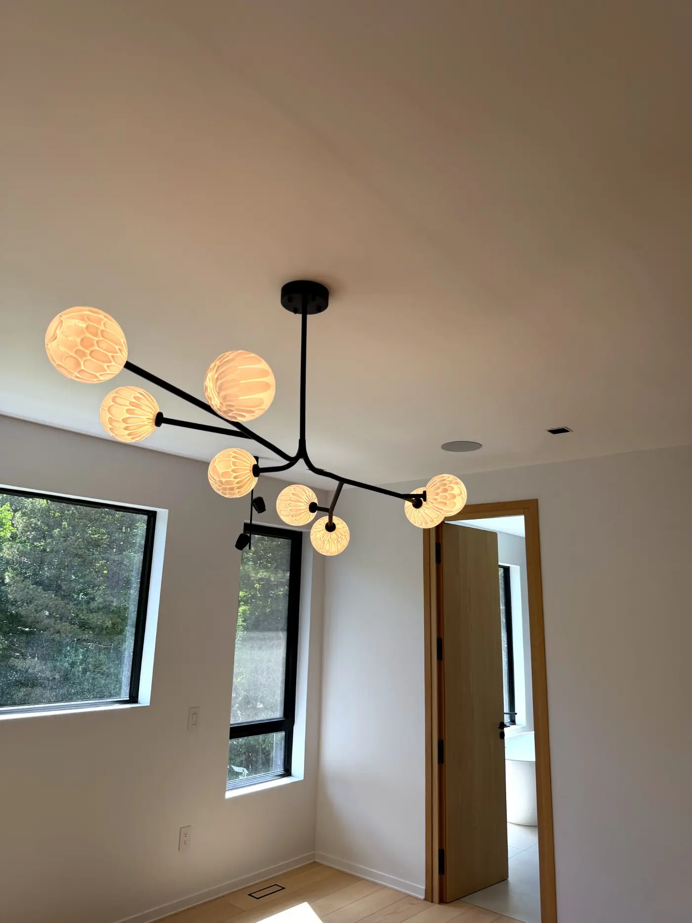 Bedroom lit by a branch fixture with globe shades